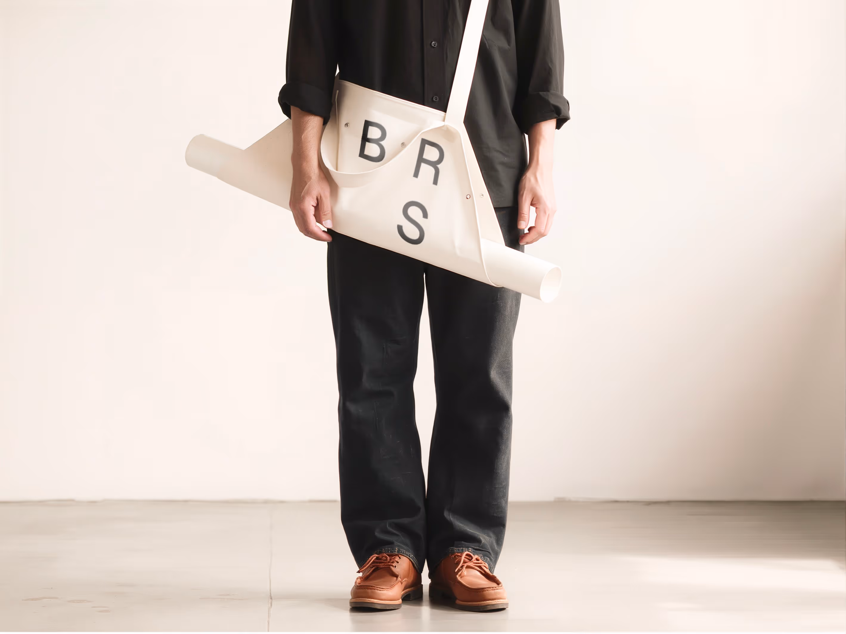 Person carrying a BRS tote bag with rolled drawings