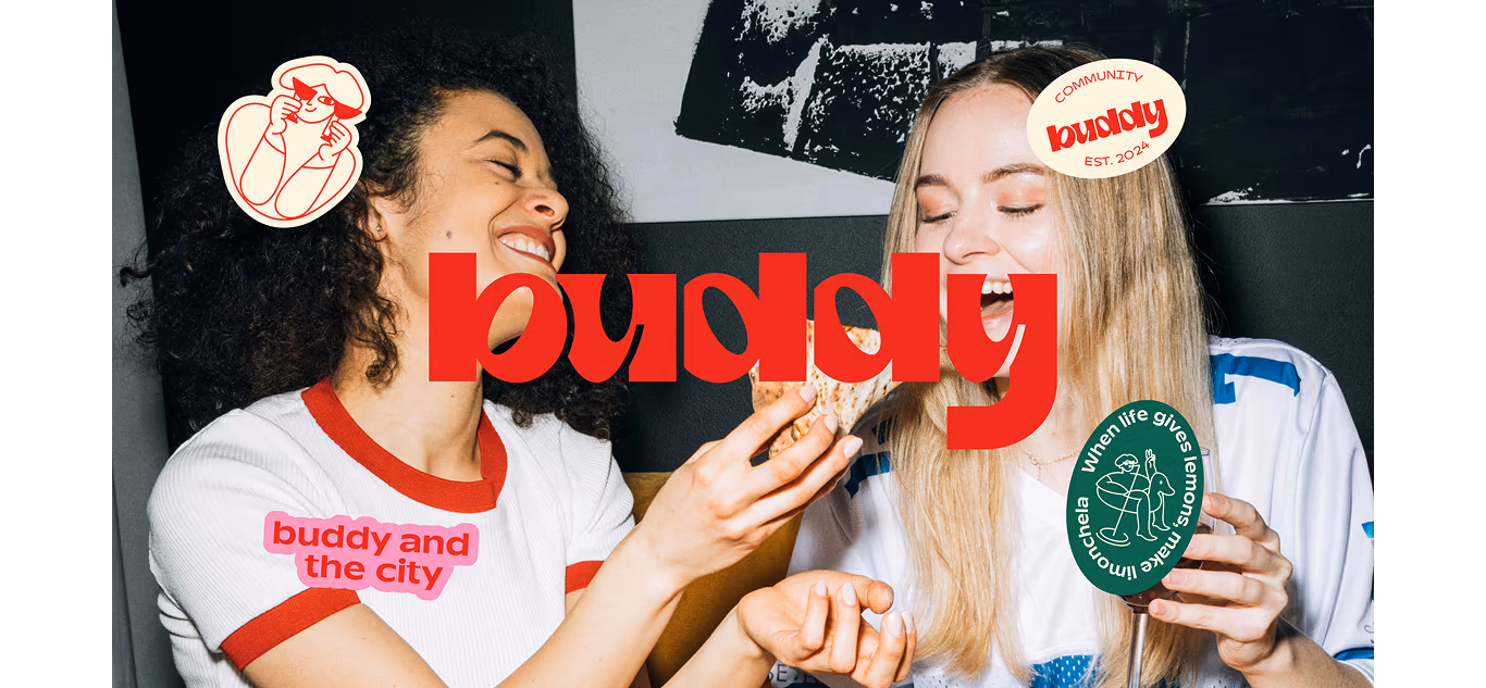 Two women in Buddy t-shirts with community stickers