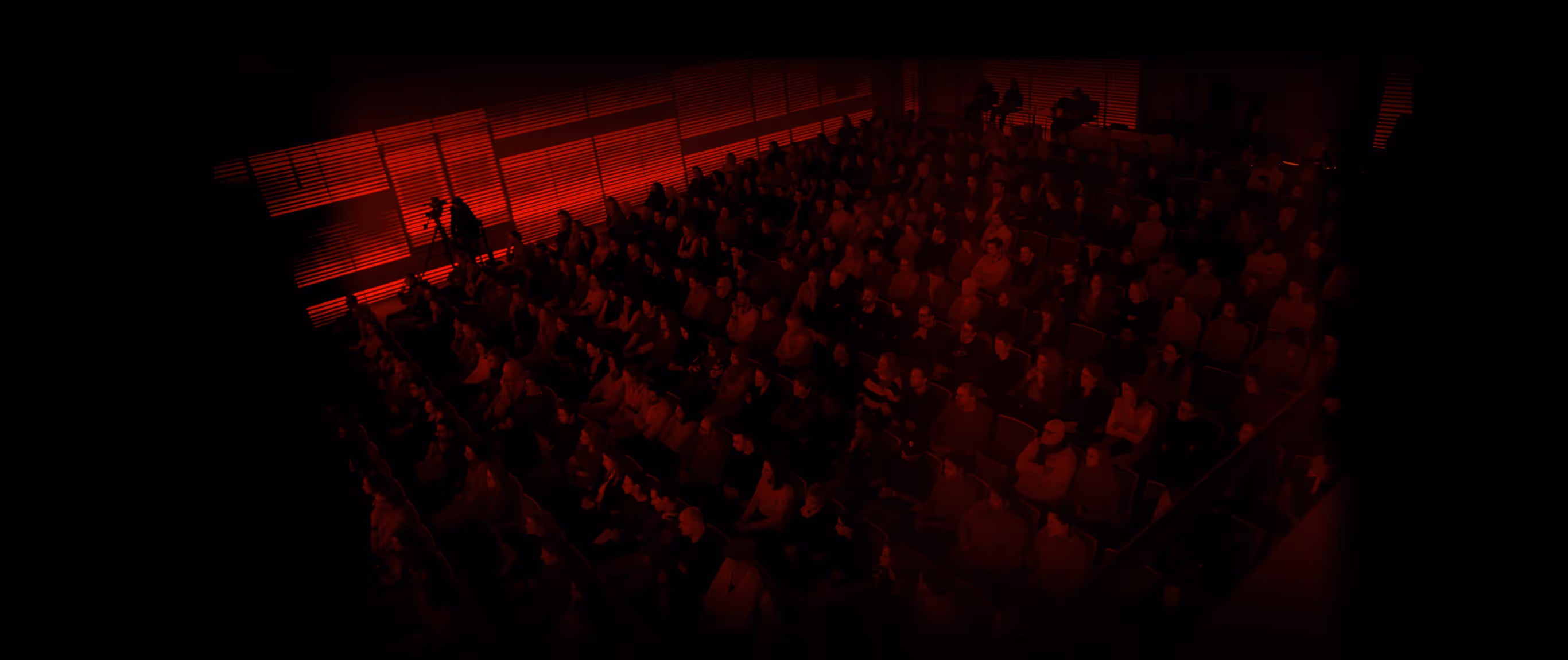 Dark auditorium lit in red before a TEDx talk