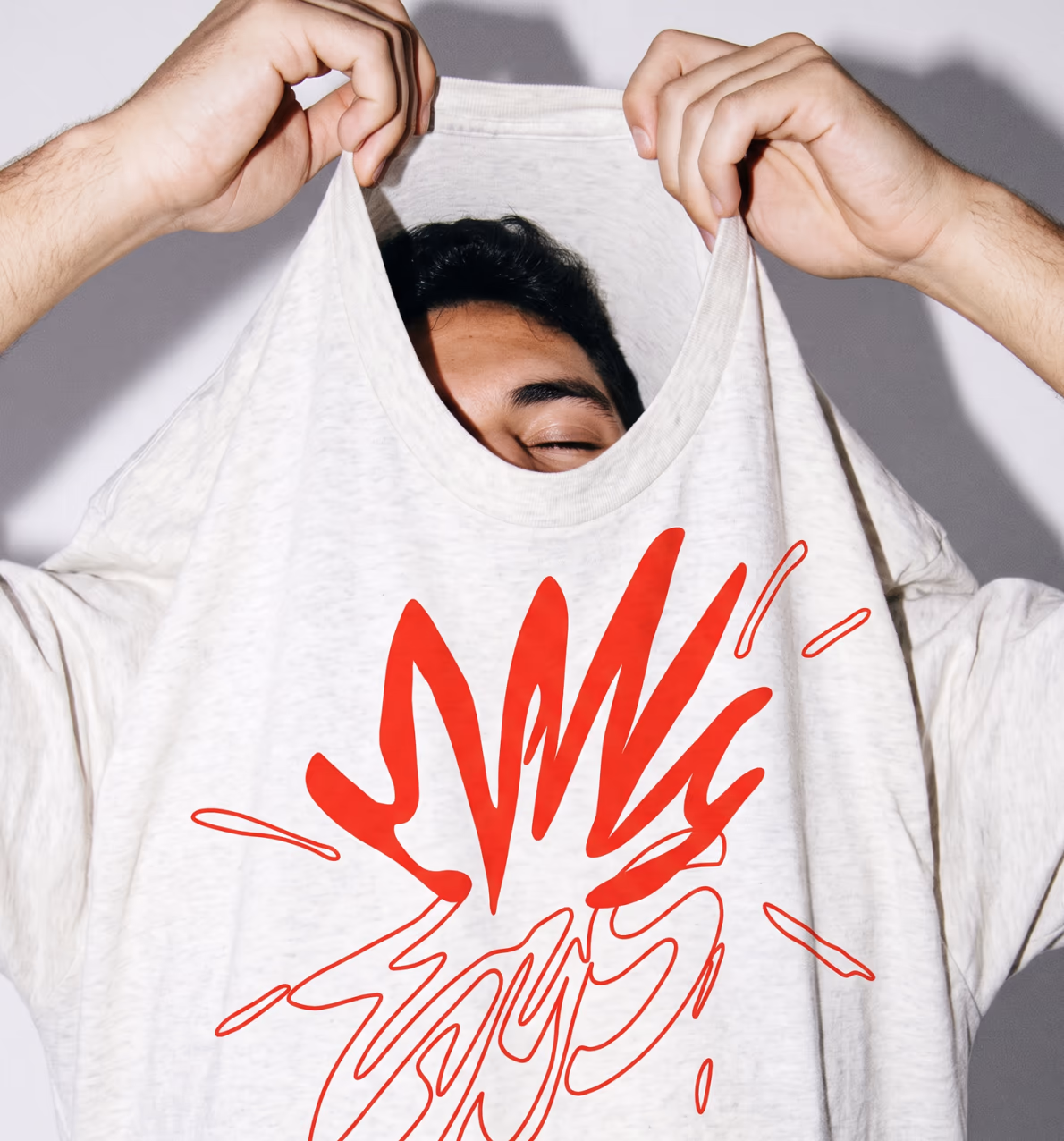 Person pulling on a T-shirt with a hand-drawn print